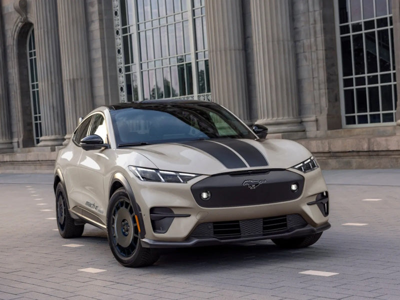 Tan SUV with black racing stripes parked in front of a building.