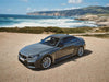 Gray car parked on a beach with ocean in the background.