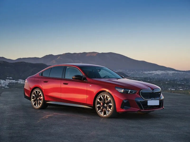 Red sedan car parked in front of mountains.