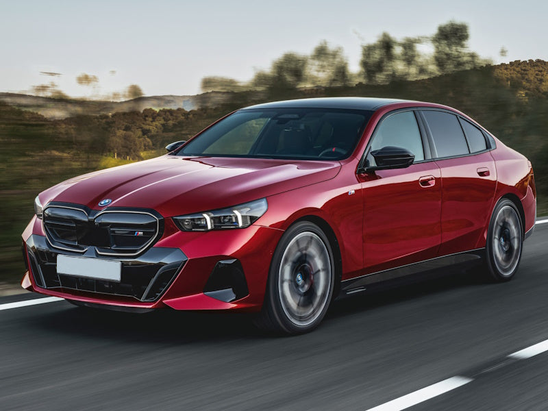 Red sedan car driving on a road.