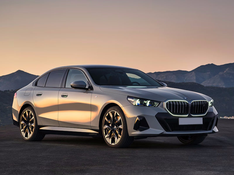 Silver BMW sedan parked on a road with mountains in the background.