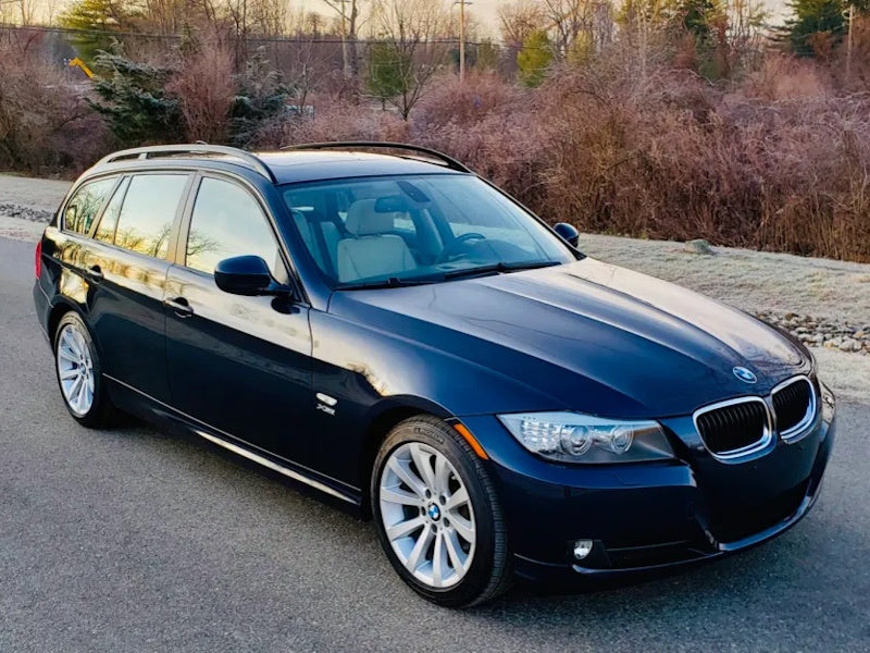 Blue BMW station wagon on a road.