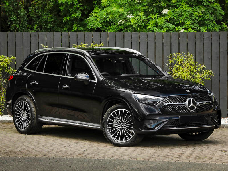 Black SUV car parked in front of a wooden fence.