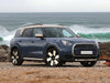Blue SUV parked on a beach with ocean waves in the background.