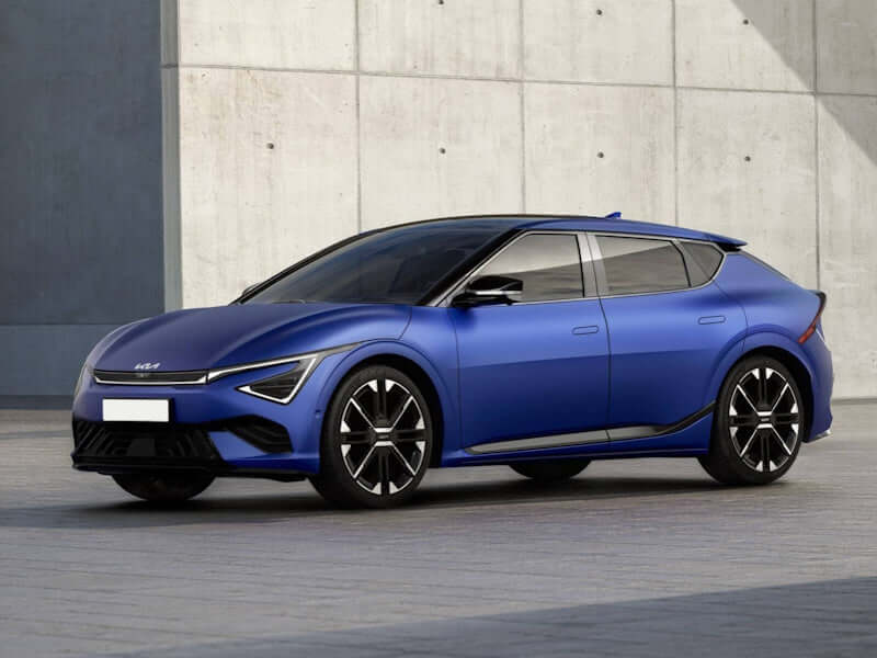 Blue Kia EV6 electric car parked near a concrete wall.