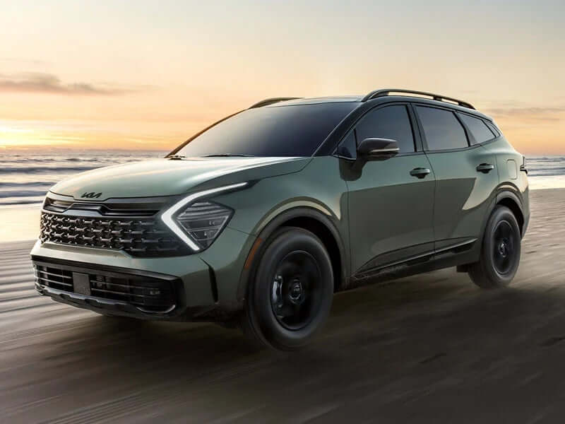 Green Kia SUV parked on a beach.