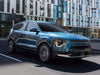 Blue Kia Niro SUV driving on a city street.