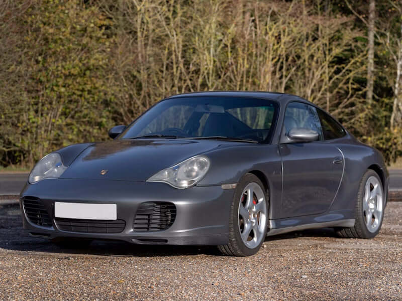 Gray sports car parked on gravel.
